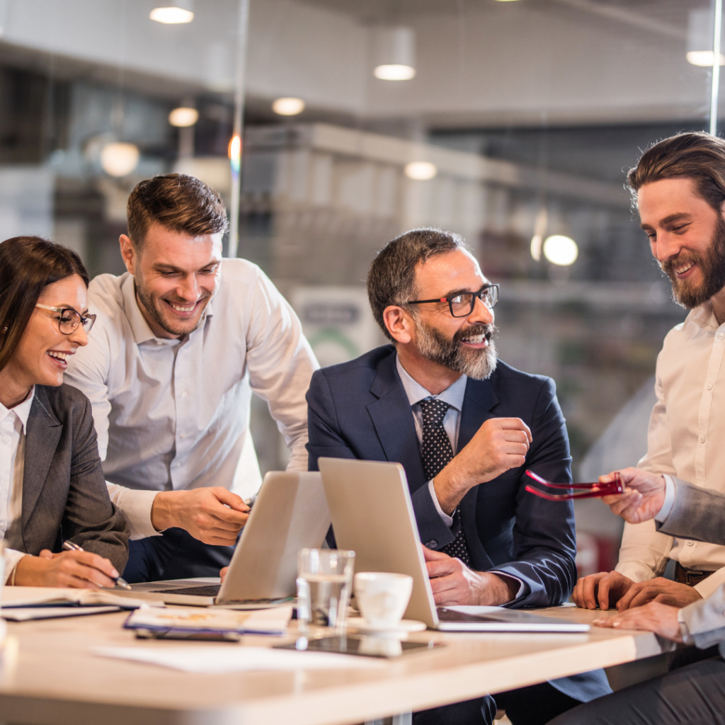 Professional team collaborating around laptop in bright office, discussing business strategy and food industry solutions together.